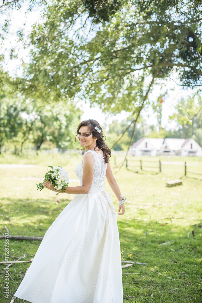 Beautiful bride outdoors on the meadow on a wedding day. Joyful moment of happiness