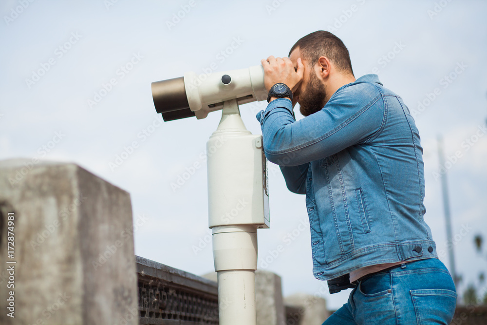 Trendy male person look in binocular telescope