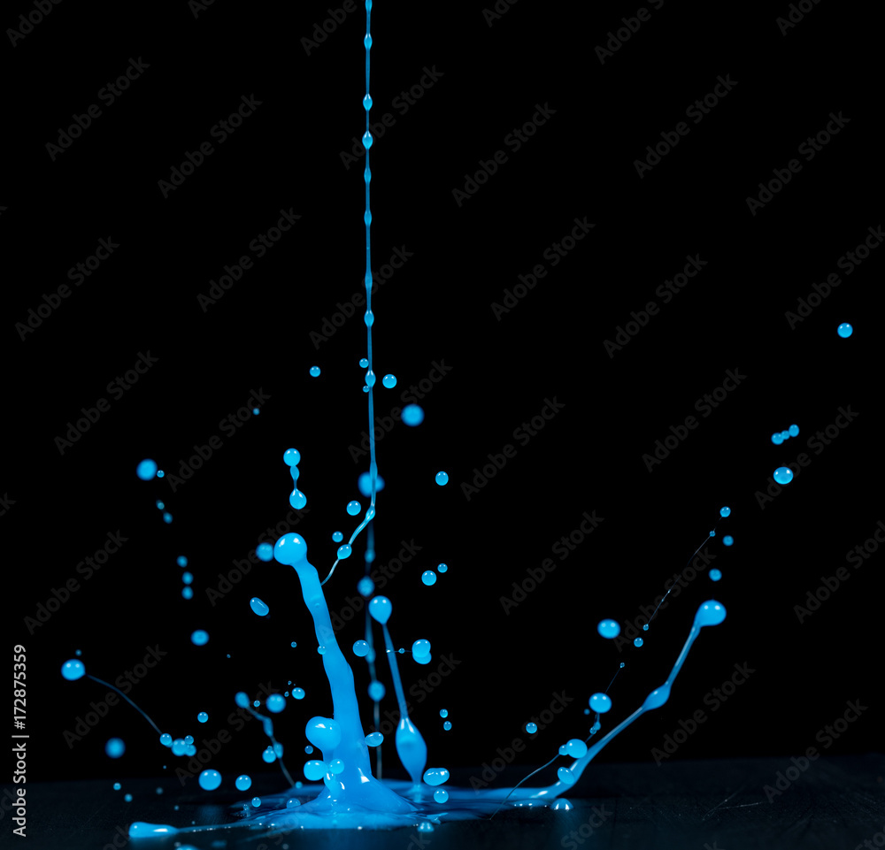 splashes of blue slime in ultraviolet light on a black background
