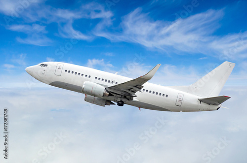 Passenger airplane flies on a flight level against a background of clouds and a blue sky