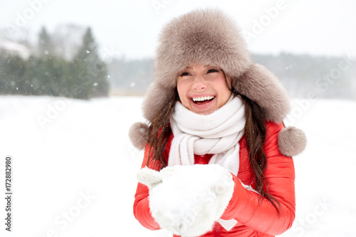 happy woman with snow in winter fur hat outdoors