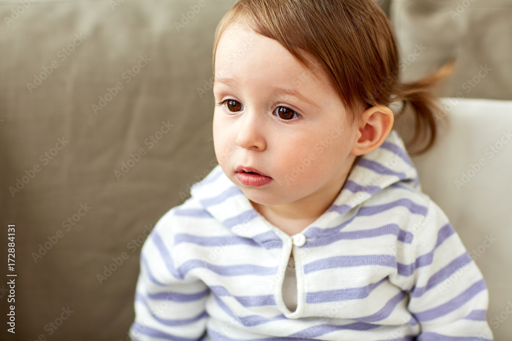 portrait of baby girl sitting on sofa at home
