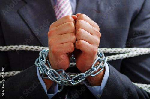 Close up of a businessman with chains in his hands, in a blurred background