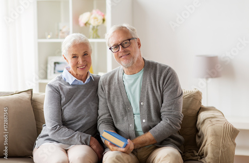 happy senior couple sitting on sofa at home