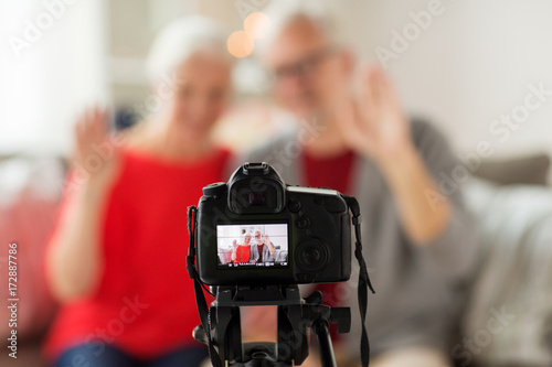 happy senior couple with camera recording video