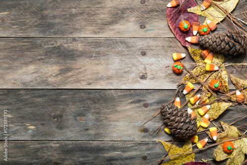 wooden table with fall scene leaves candycorn pine cones top view