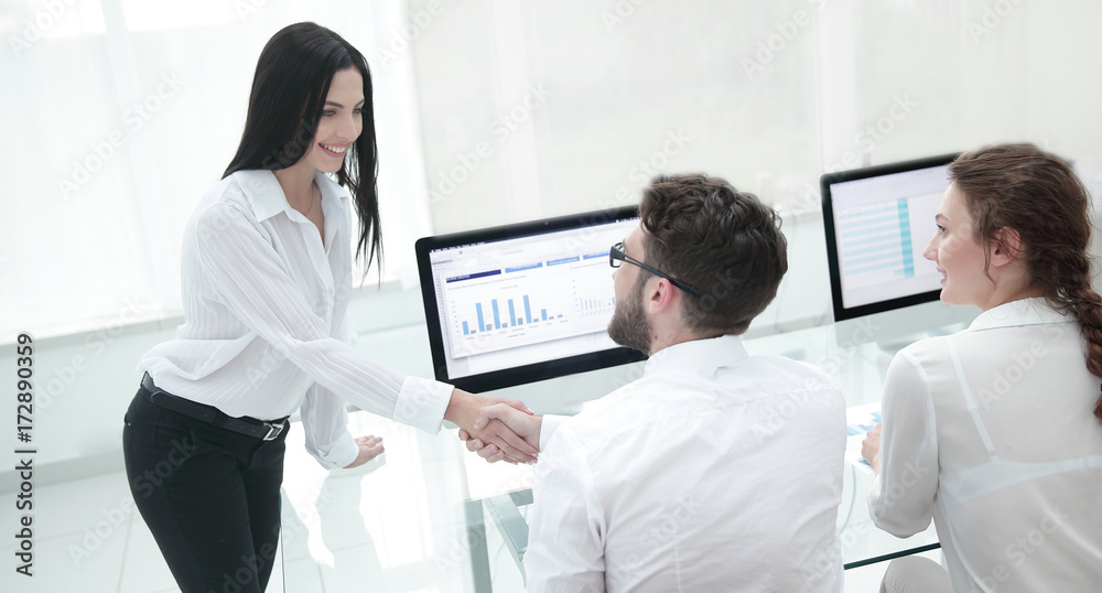 employees greet each other with a handshake near the desk employees greet each other with a handshake near the desk