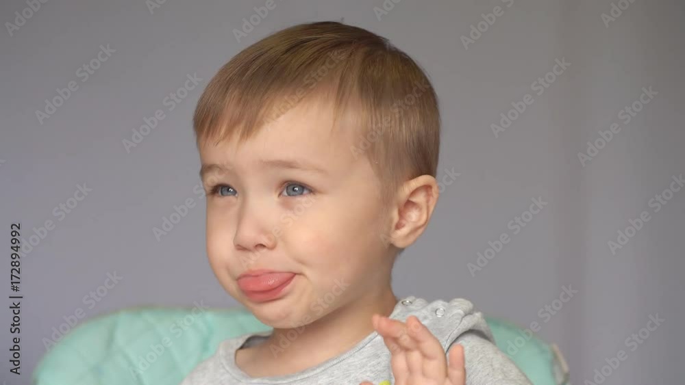 Cute boy laughs and shows the tongue sitting in the kitchen Cute boy laughs and shows the tongue sitting in the kitchen