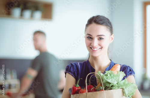 Young couple in the kitchen , woman with a bag of groceries shopping photo