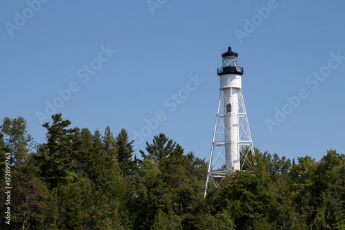 White lighthouse over treetops in Lake Superior on an Apostle Island