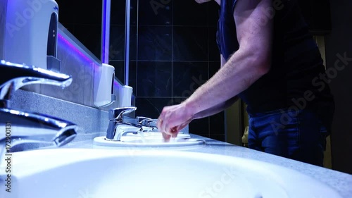 A man washes his hands with soap in the sink in the toilet photo