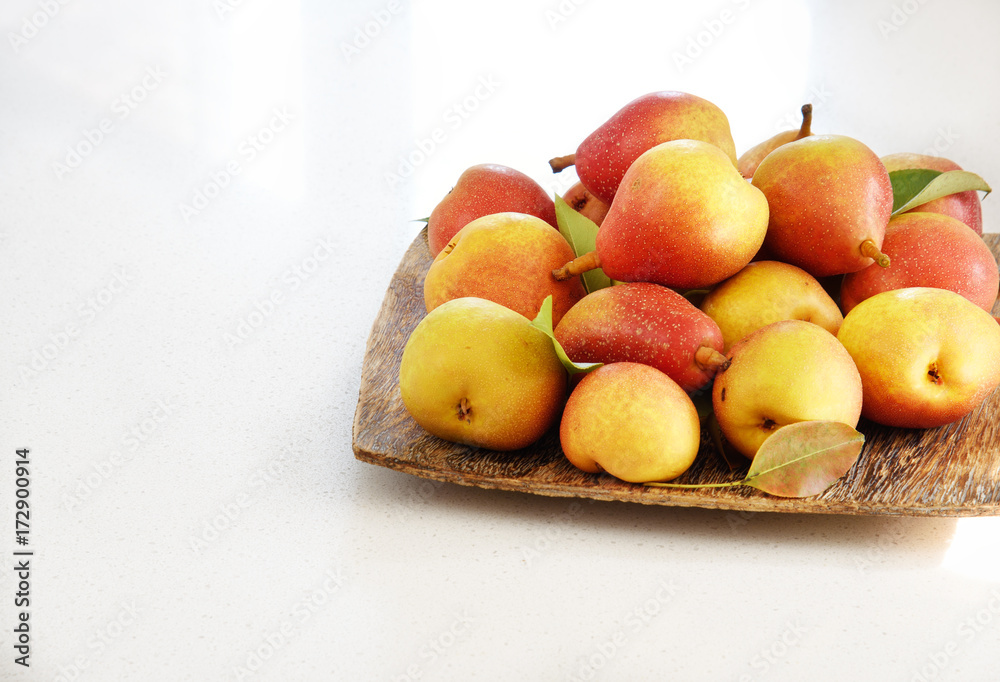 Juicy pears on the wooden plate on the white background Juicy pears on the wooden plate on the white background