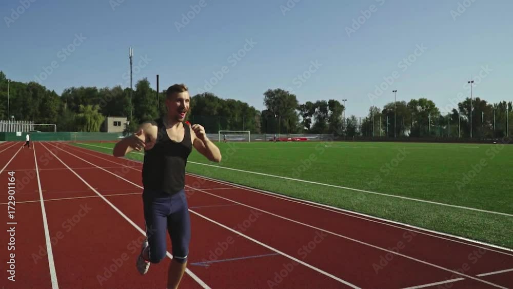 Happy bearded athlete runs along the track and sucks a lollipop Happy bearded athlete runs along the track and sucks a lollipop