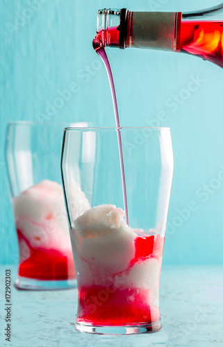 Preparation of cocktail Terremoto. Chilean traditional alcoholic drink Terrremoto. with pineapple ice cream, liquor grenadine, pisco and white wine. Blue background photo