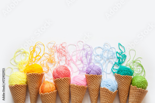Canvas Print Balls of yarn lie in a waffle cone for ice cream. Coloured wool.