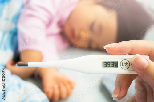Close-up mother's hand holding thermometer. Taking child's temperature. photo