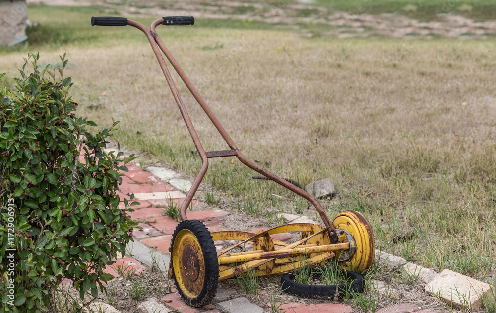horizontal image of an old vintage antique manual push mower with a