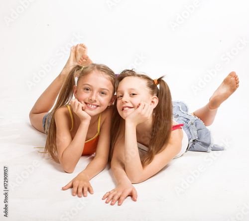 Two beautiful girls laying on white