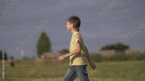 farmer boy is walking along the harvested field photo
