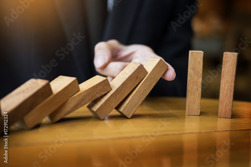 businessman hand stop dominoes continuous toppled or risk with copyspace.