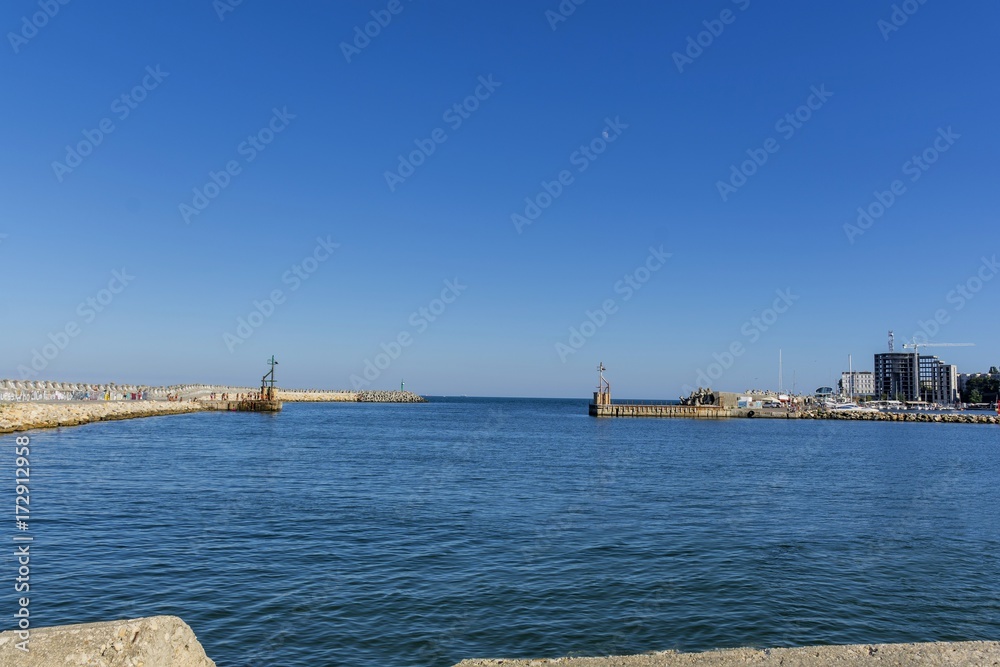 Bay view of the port town of Tomis, Constanta. Small Constanta harbour gateway view. Sea wall for protect the beach. Breakwaters concrete tetra-pods.