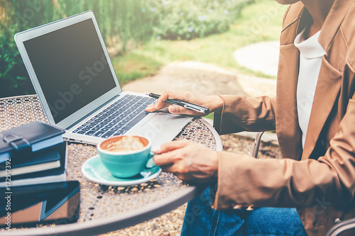Young business female using laptop while she is relaxing in coffee shop in the fresh air