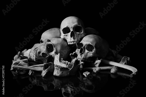 The human skull and pile of bones on black background, Halloween night, Still life style, art.