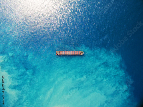 Large bulk carrier ship sailing in open ocean top down aerial shot