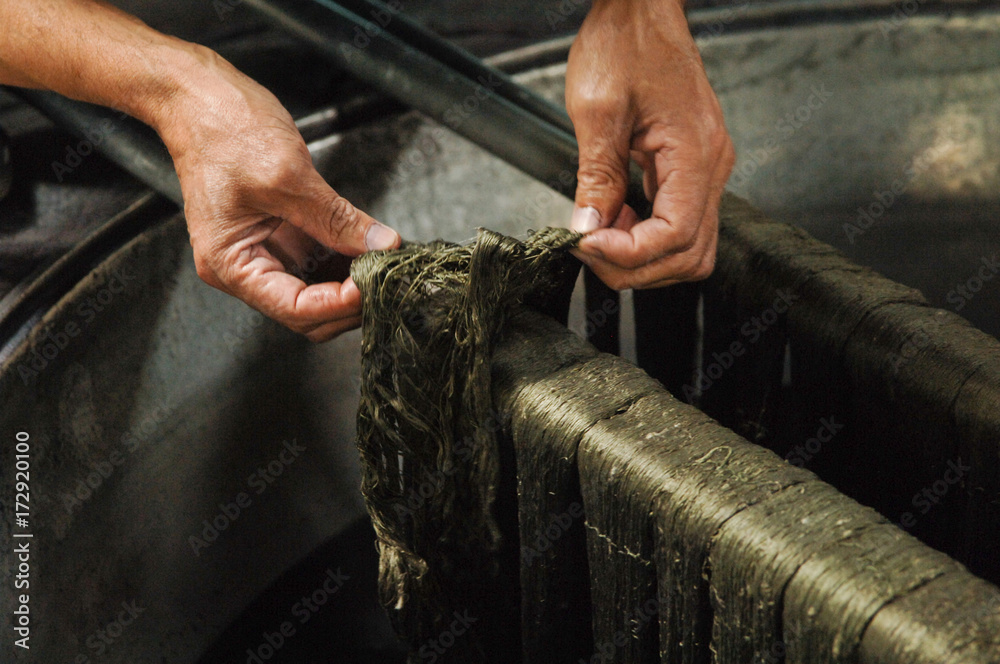 painting threads and yarns. male hands paint the cloth in the trough