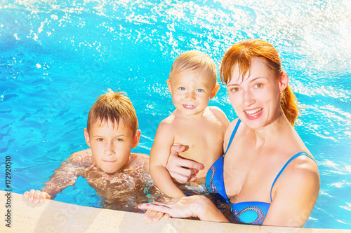 Happy family smiling at swimming pool background. © Mayatnikstudio