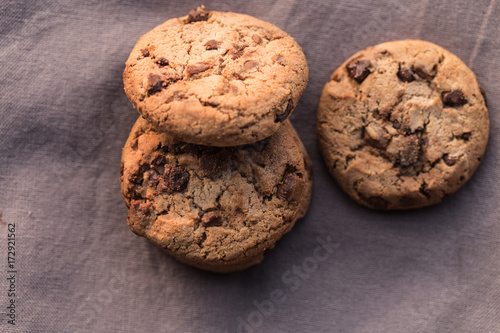 Stack of chocolate chips cookies on brown background