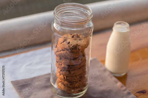 Chocolate chips cookies in bottle and a bottle of milk on wooden table