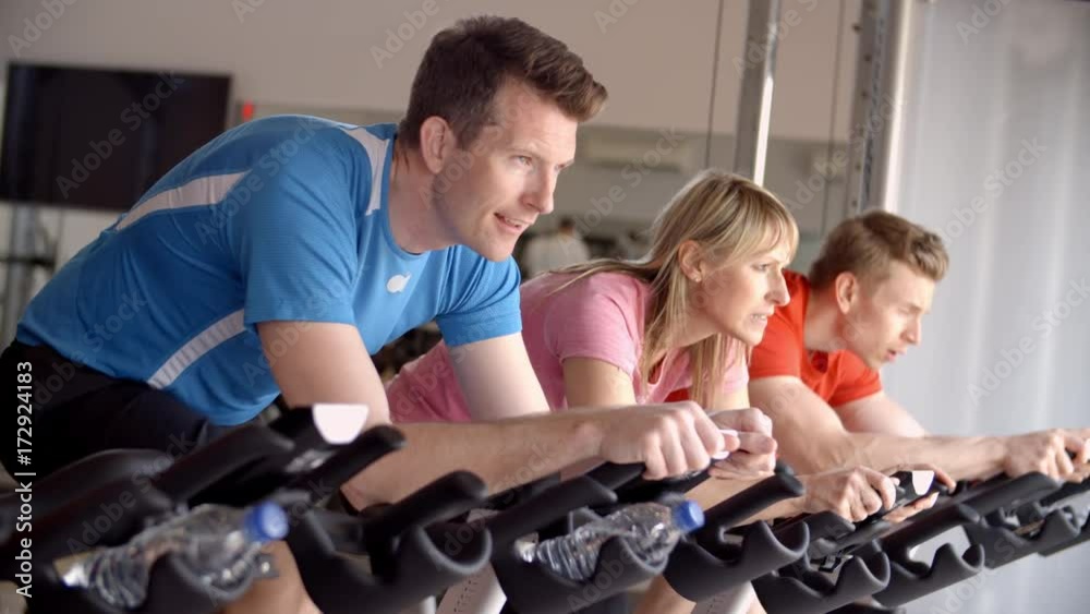 Side view of a spinning class on exercise bikes at a gym