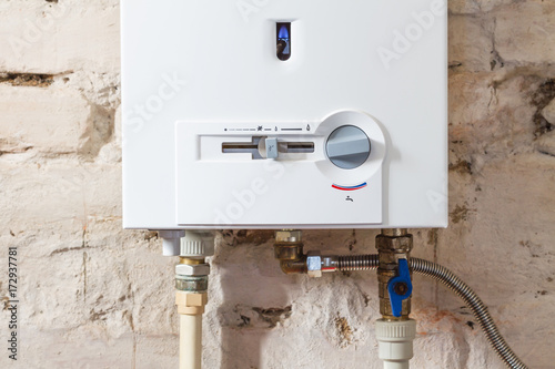 Closeup of gas water heater on a brick wall. Gas boiler in boiler room for hot water photo