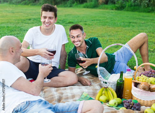 Three smiling male friends enjoying life on picnic outdoors © JackF