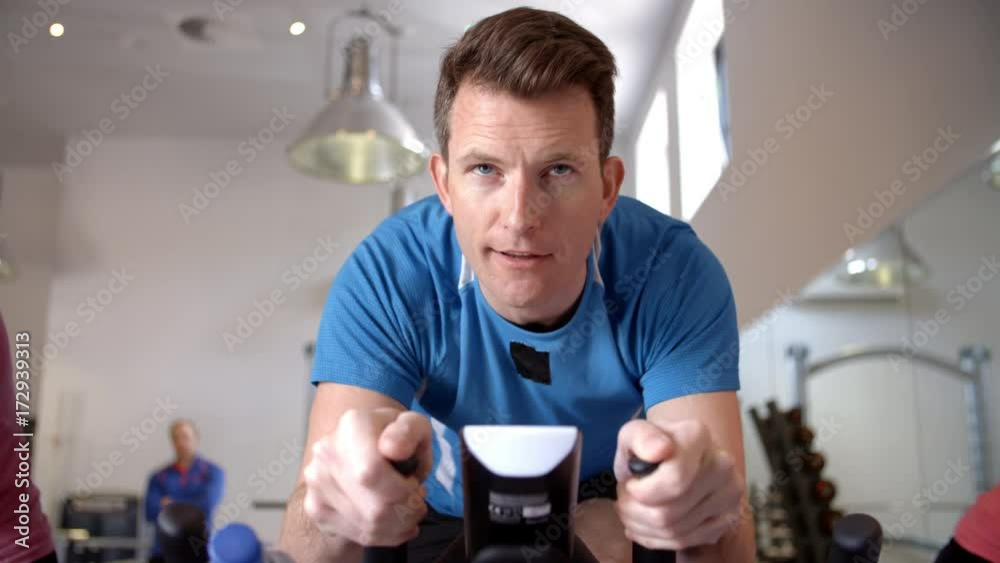 Man on an exercise bike in a spinning class at a gym, close up Man on an exercise bike in a spinning class at a gym, close up