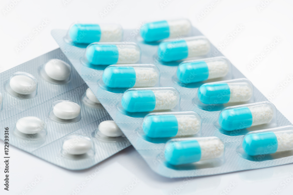 Blue capsule medicines and tablets. Close up of blue capsules and tablets on white background.

