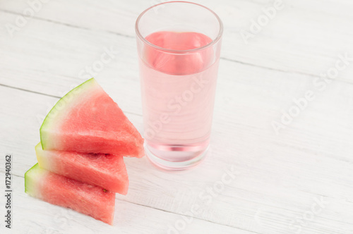 Cuadro en lienzo Three slices of fresh ripe watermelon and juice in transparent glass on old wood