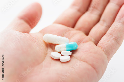Blue capsule medicines and tablets in male hand. Prescription drugs. Concept image of medication.
