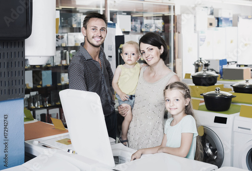 parents with two kids choosing washing machine in home appliance store