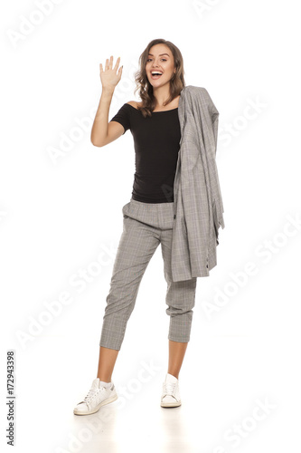 happy young beautiful woman in a jacket, blouse and trousers waving hand