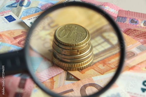 Tas de pièces derrière une loupe et billets en euros photo