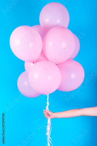 Girl hand holding pink air balloons on blue background, free space. Pink birthday balloons. Concept of love, happiness, birthday, valentine. Happy holiday pink balloons