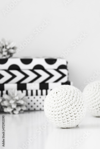 White crochet Christmas balls with modern gifts and pine cones.