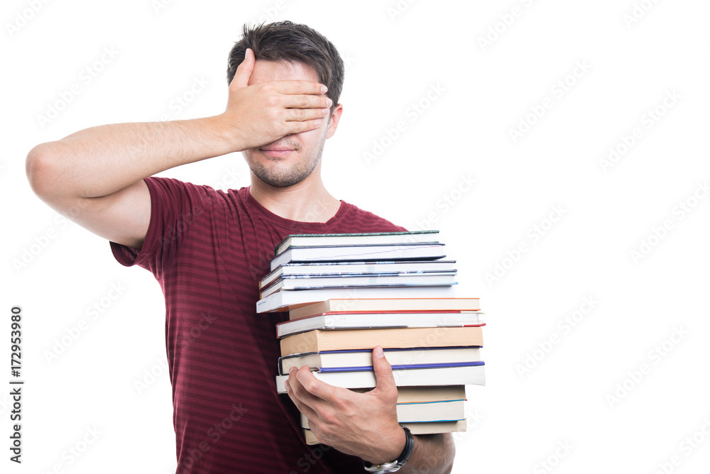 Handsome student holding pile of books covering eyes Handsome student holding pile of books covering eyes