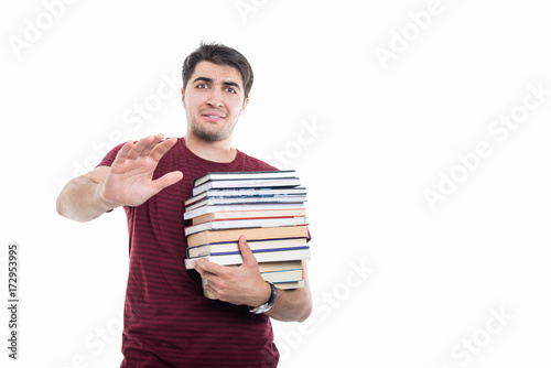 Handsome student holding pile of books looking scared