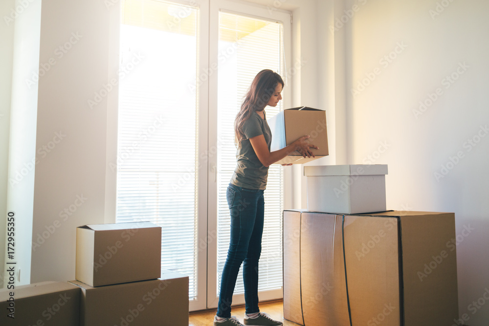 Young woman holding cardboard box. Moving into new home