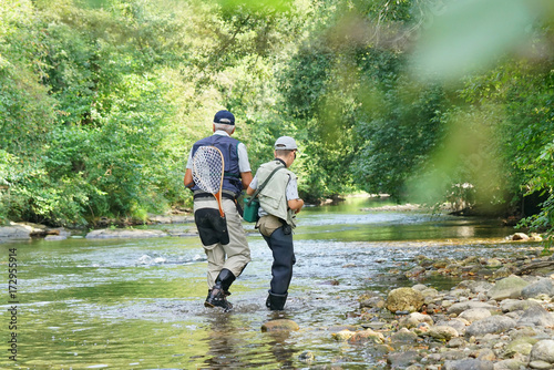 back view of father and son fly-fishing in river