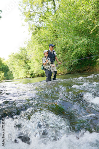Father and son fly-fishing in river