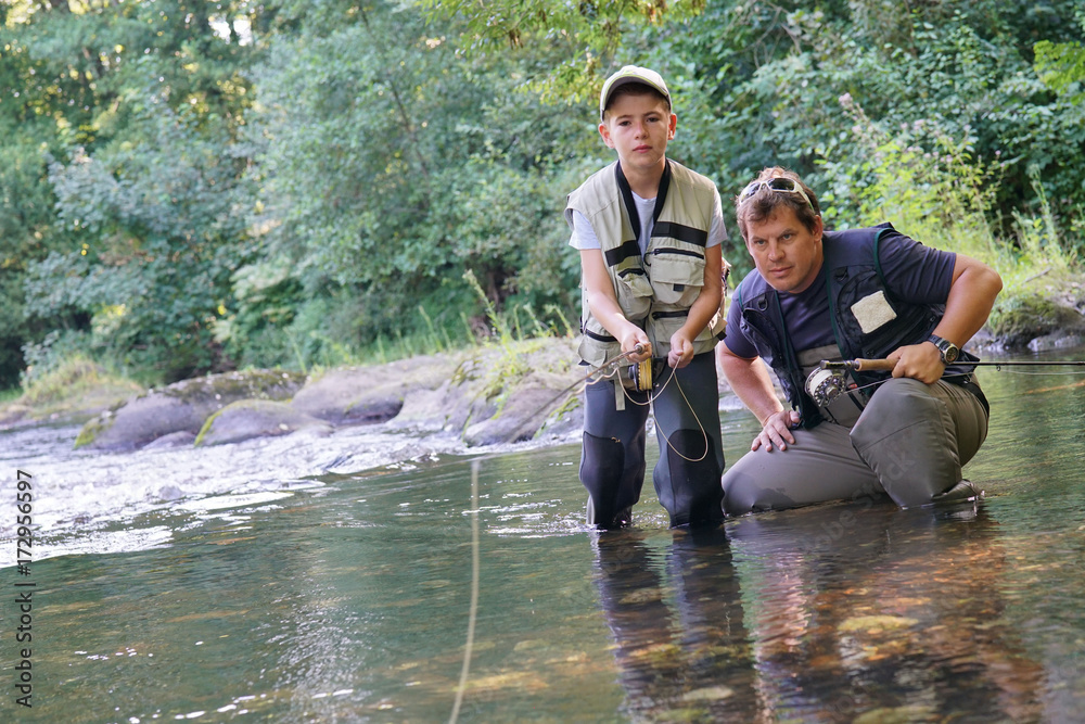 Father teaching son how to fly-fish in river Father teaching son how to fly-fish in river